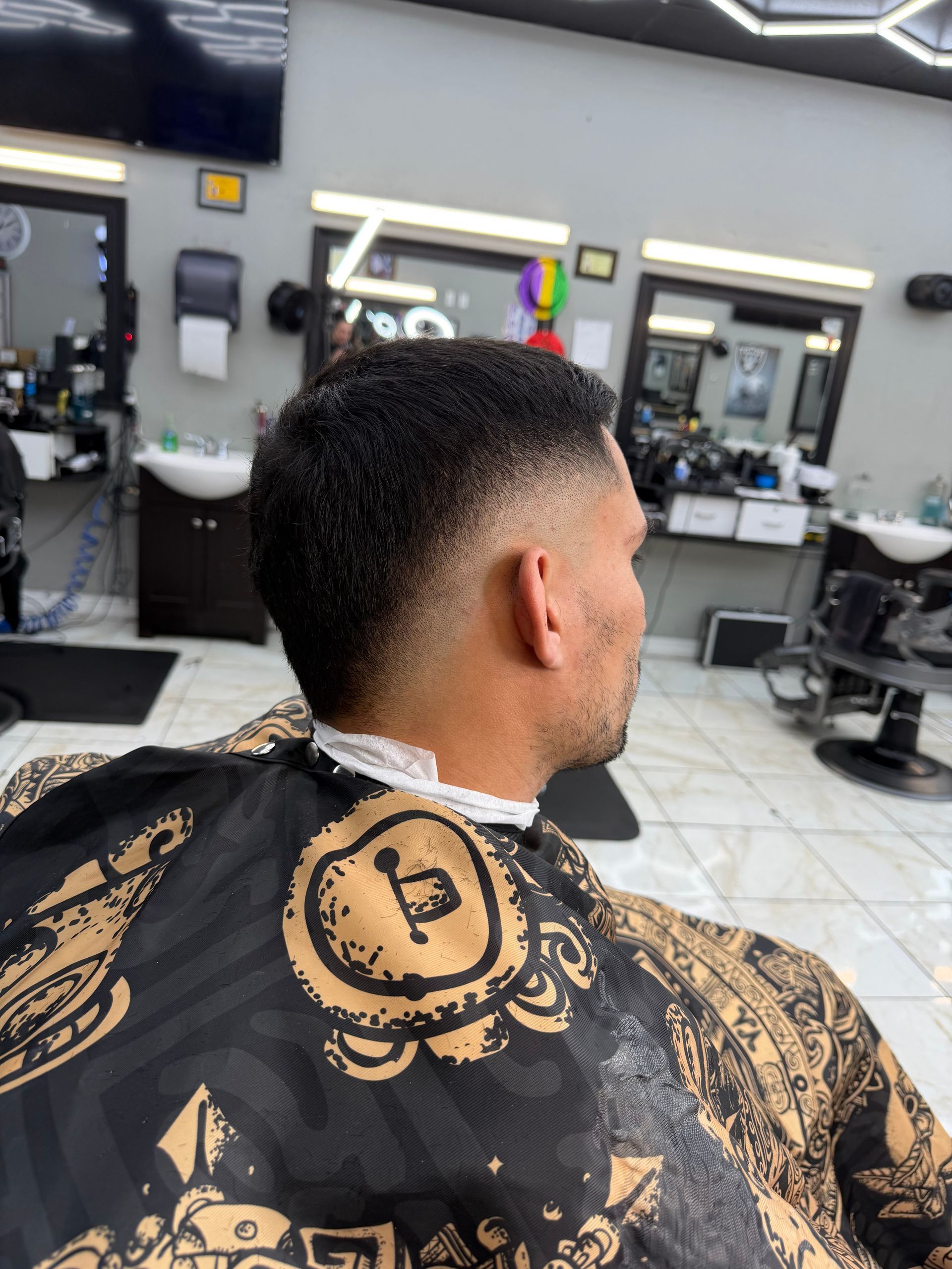 Man in a barber's chair with a faded haircut, getting ready to be styled.