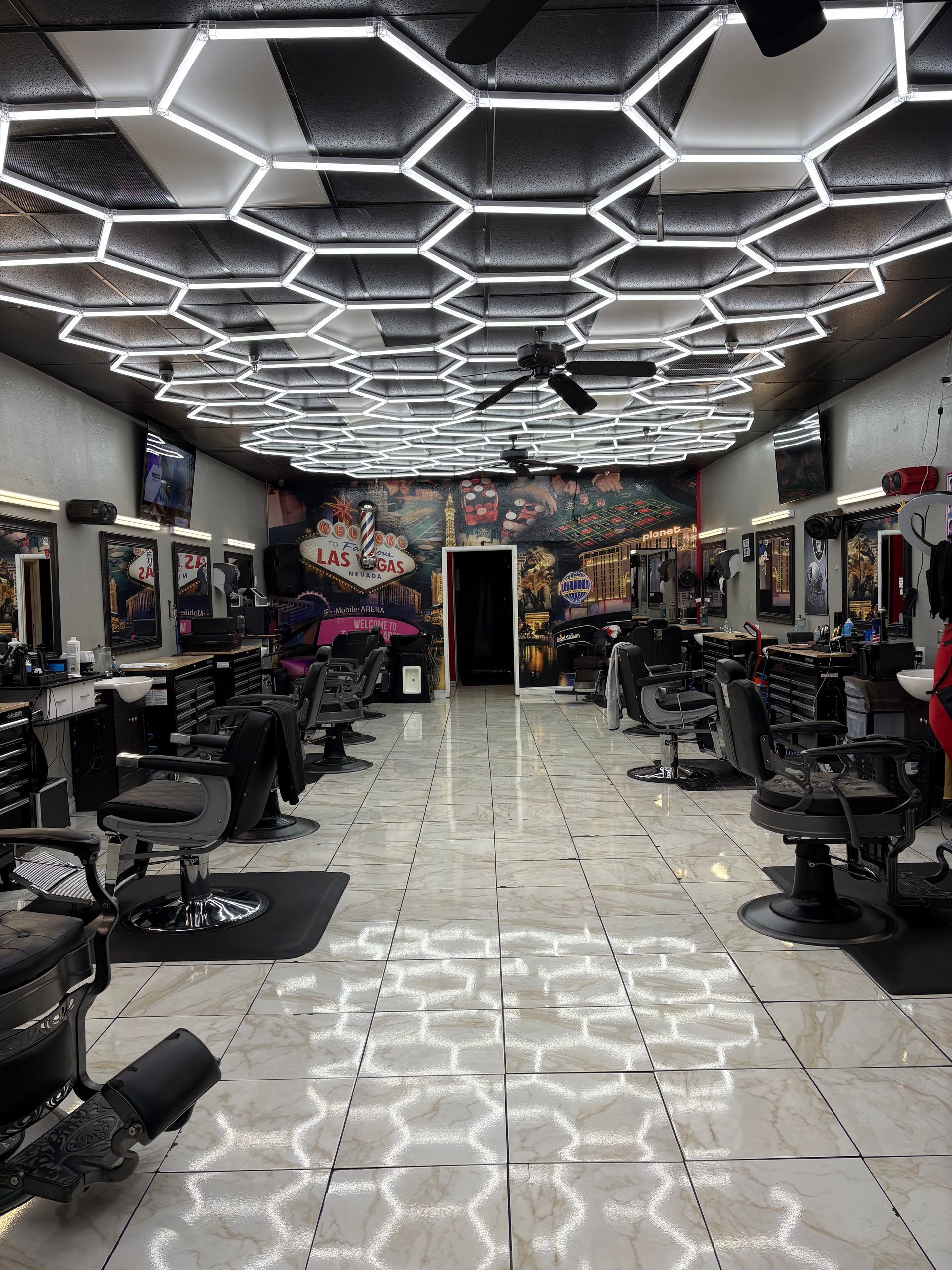 Barber shop interior with hexagonal ceiling lights, chairs, and mirrors.