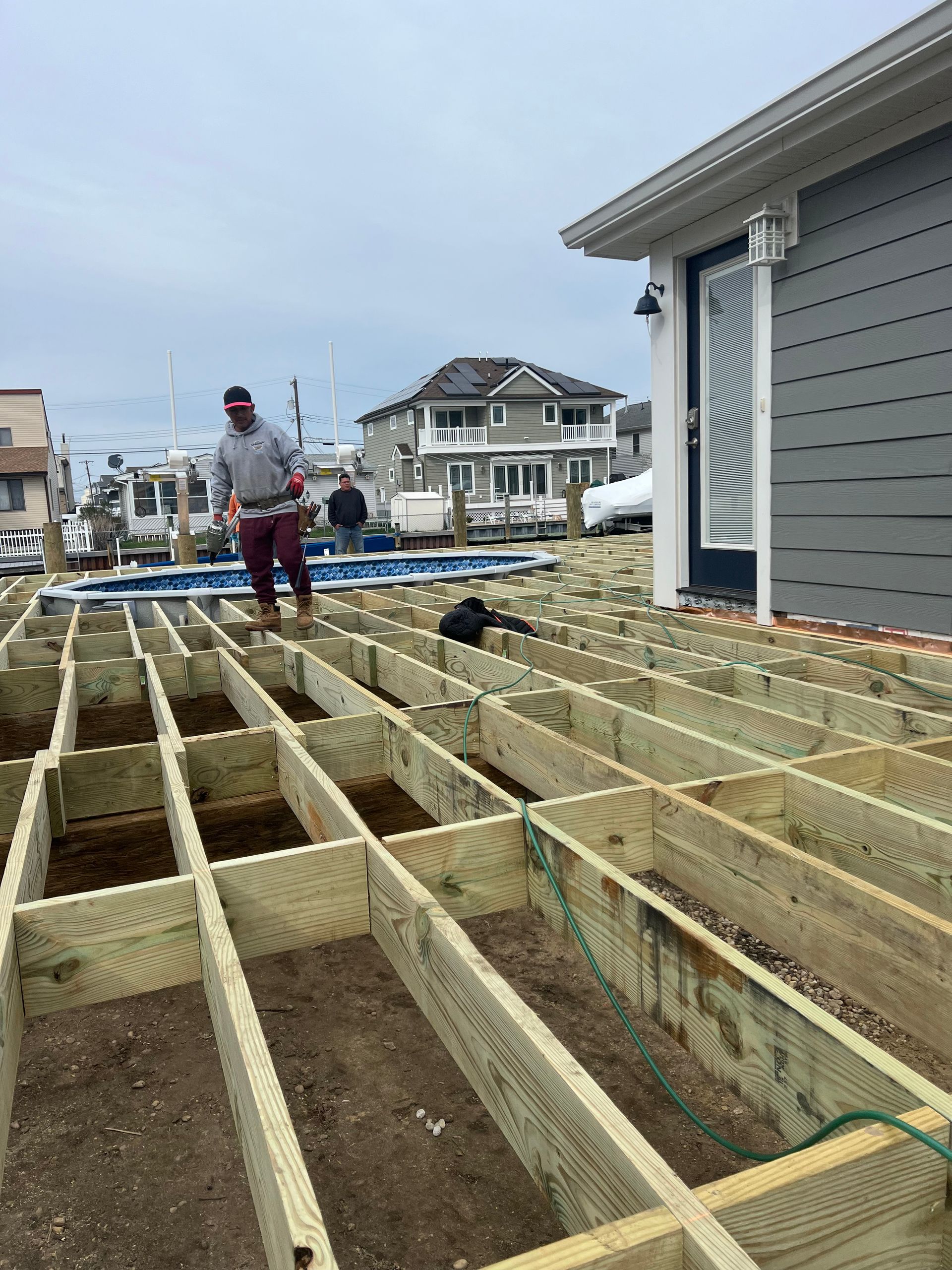 A man is standing on a wooden deck under construction.