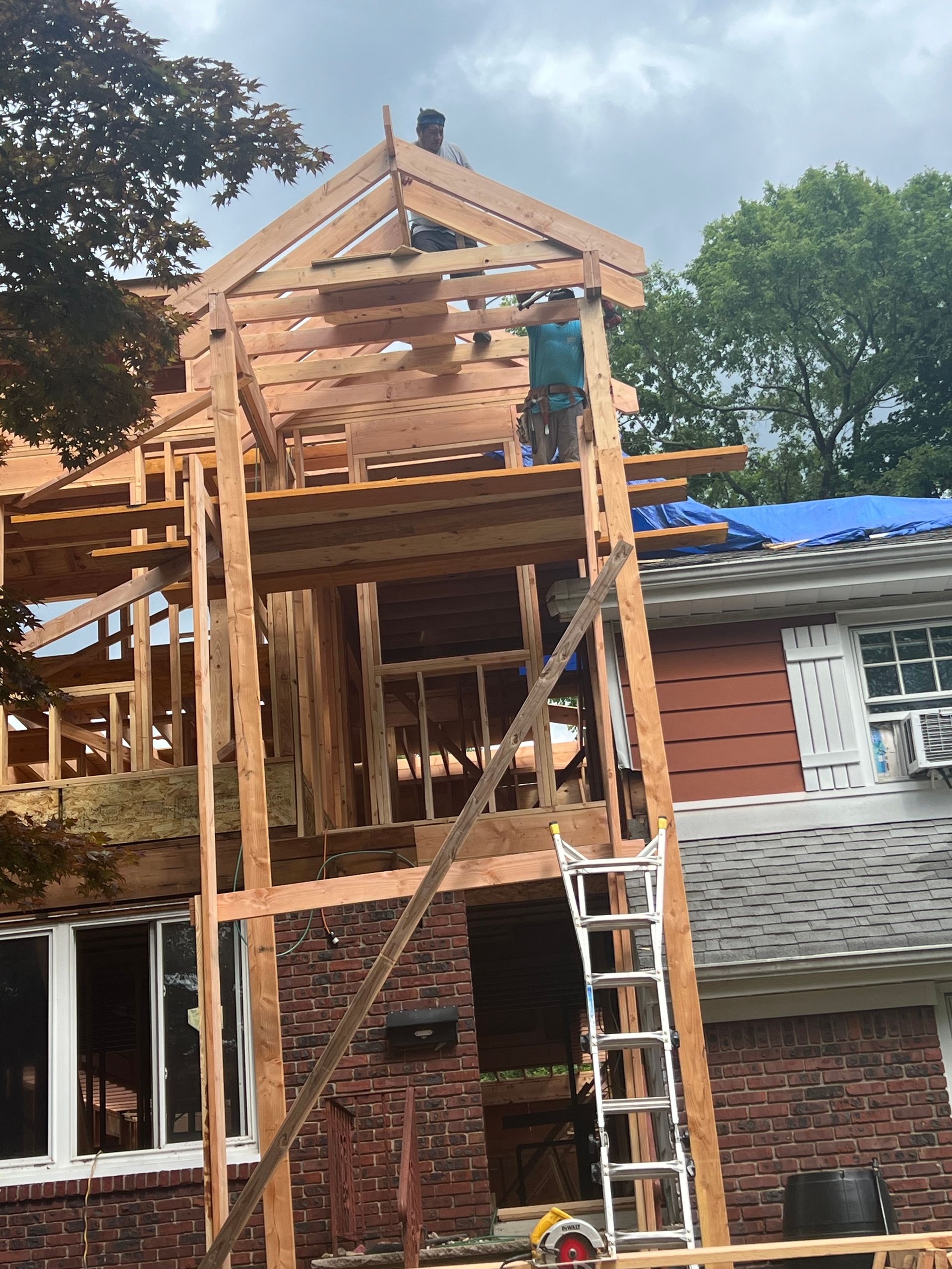 A wooden structure is being built on top of a brick house.