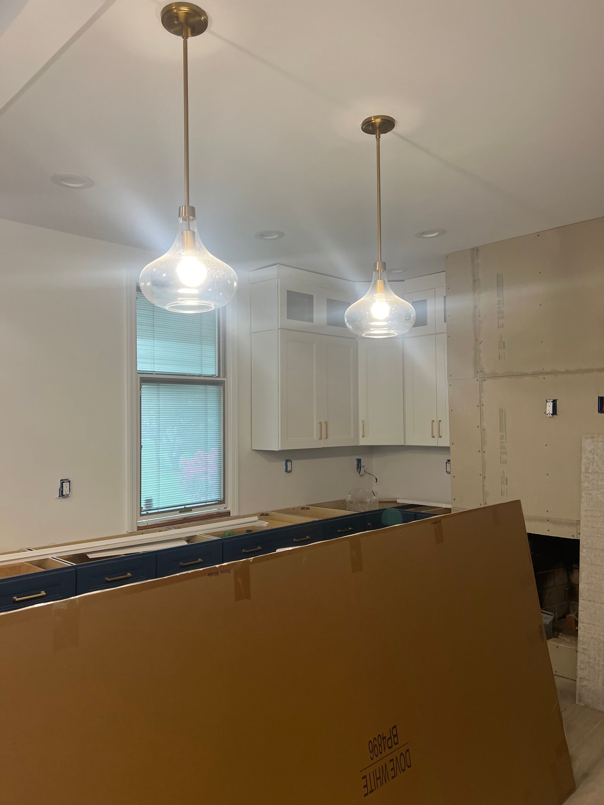 A kitchen under construction with two pendant lights hanging from the ceiling.