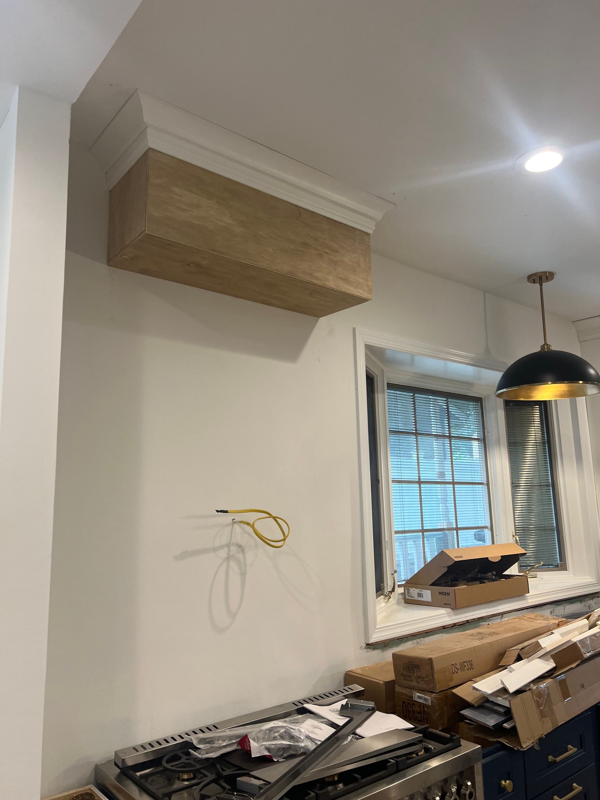 A kitchen under construction with a stove and a window.