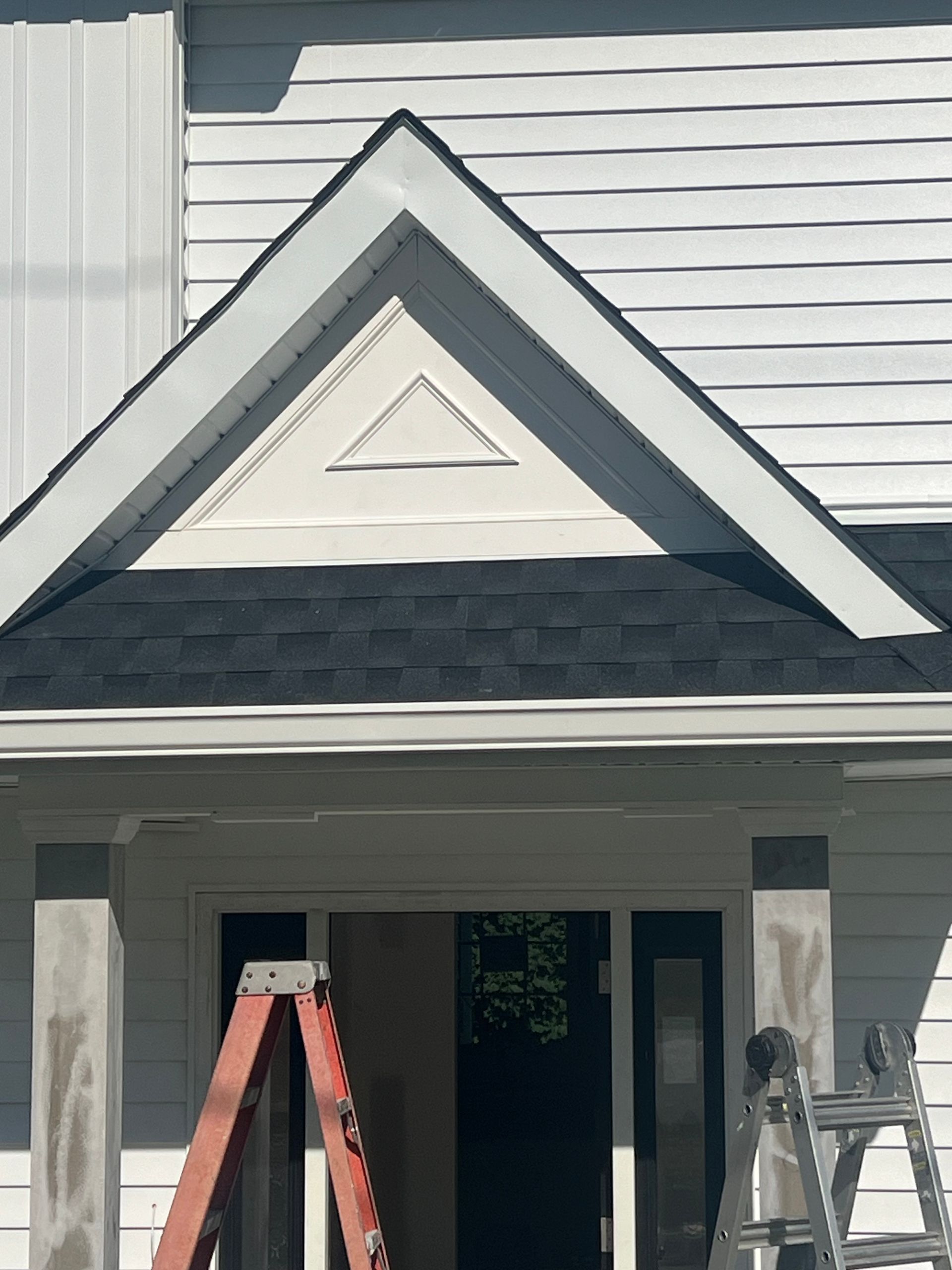 A ladder is sitting on the porch of a house.