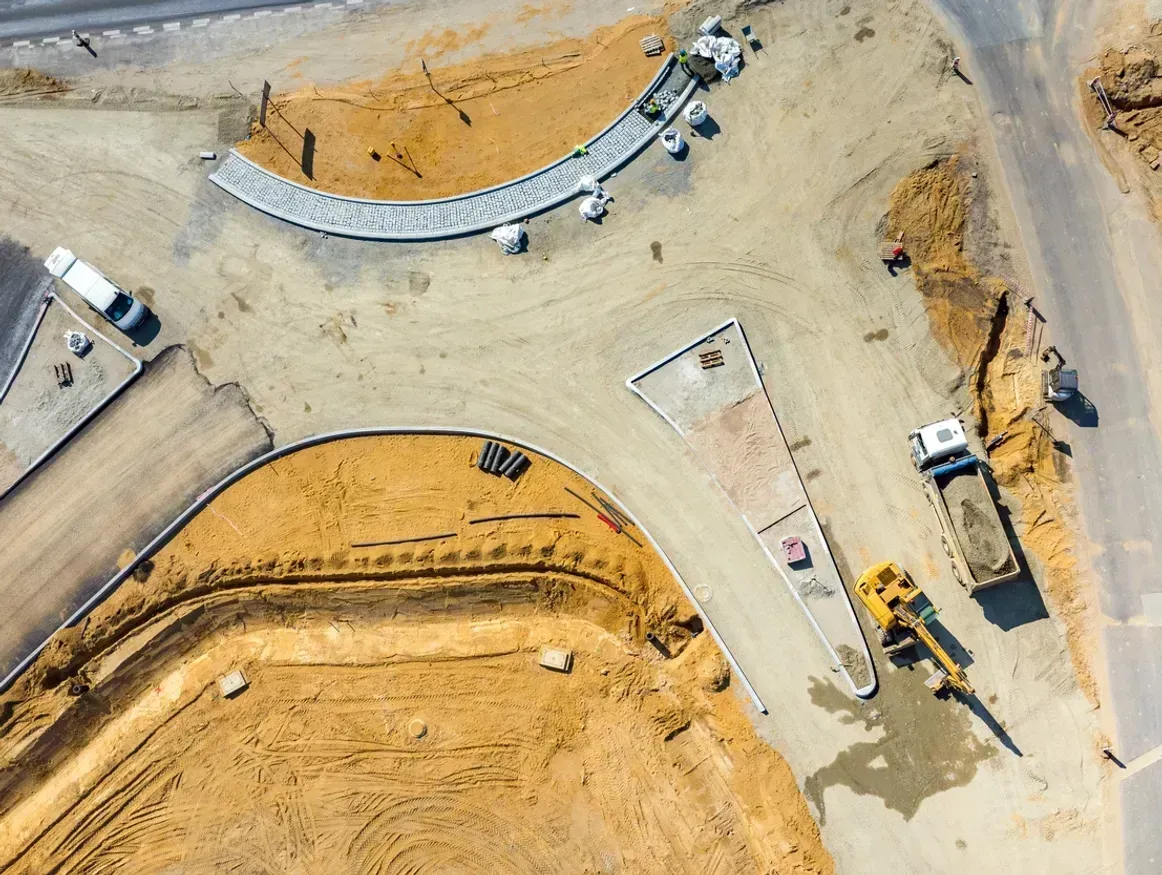 Tres personas vestidas de traje y corbata se encuentran de pie en un moderno atrio de varios niveles, mirando hacia arriba para contemplar la arquitectura.