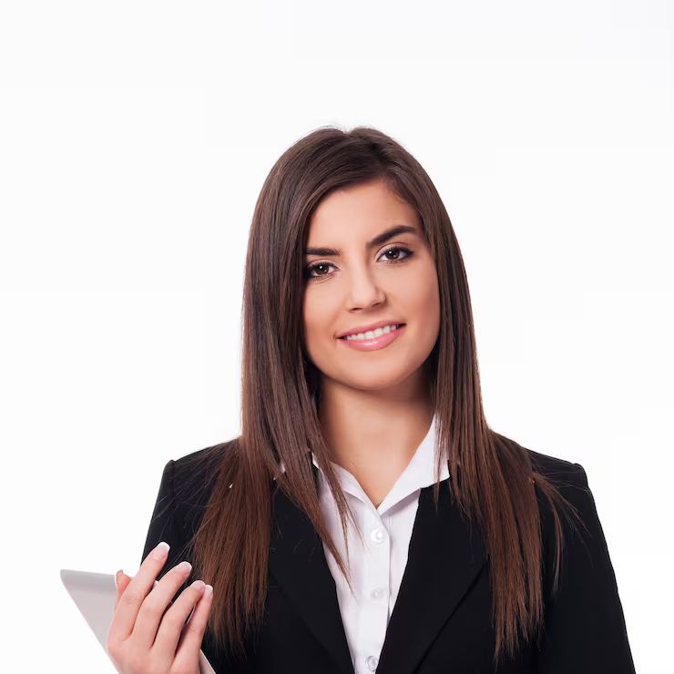 Un profesional vestido con un blazer negro y una camisa blanca sostiene una tableta y sonríe sobre un fondo blanco liso.