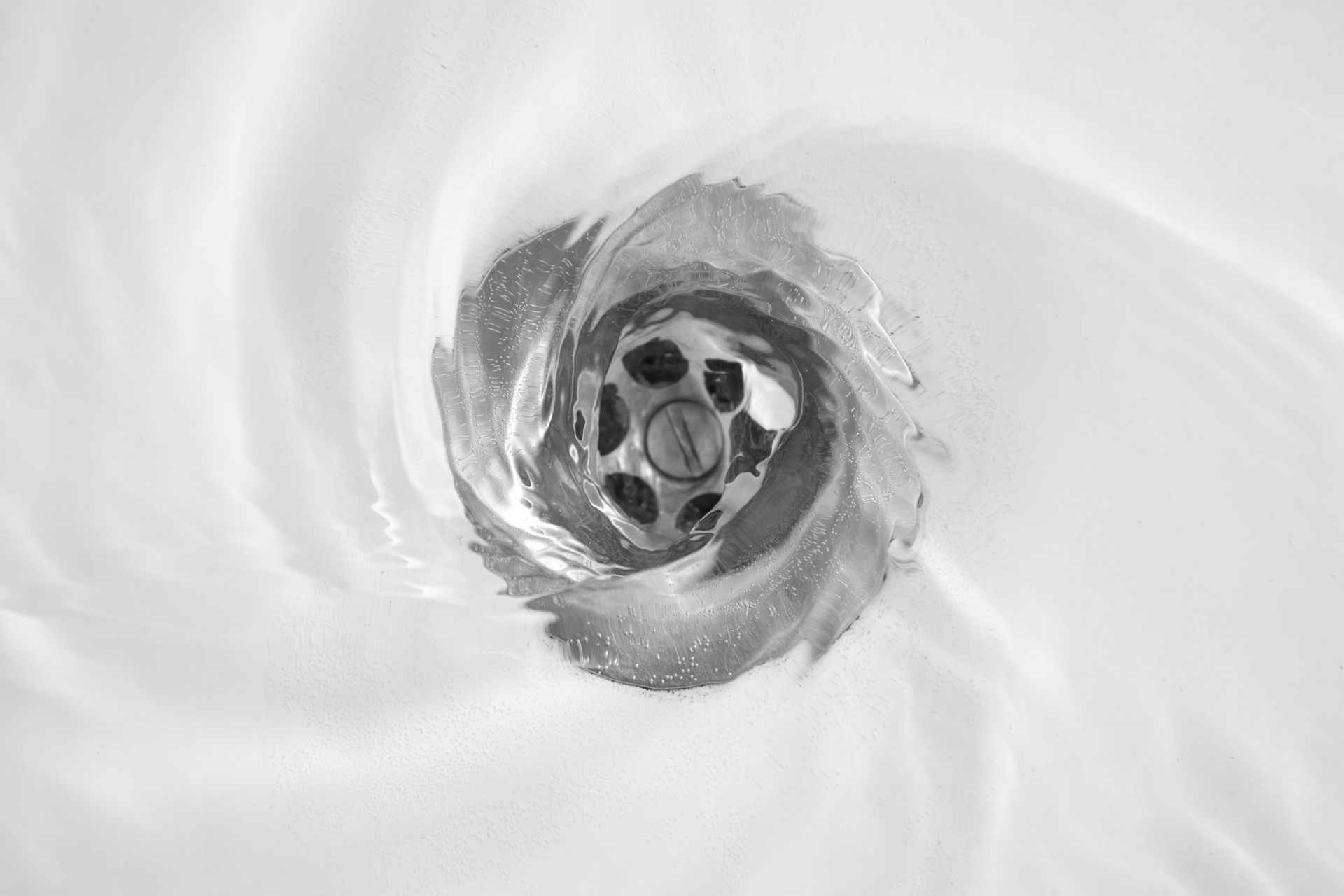 A monochrome photo of a sink drain, representing drain cleaning services available in Pekin, IL.