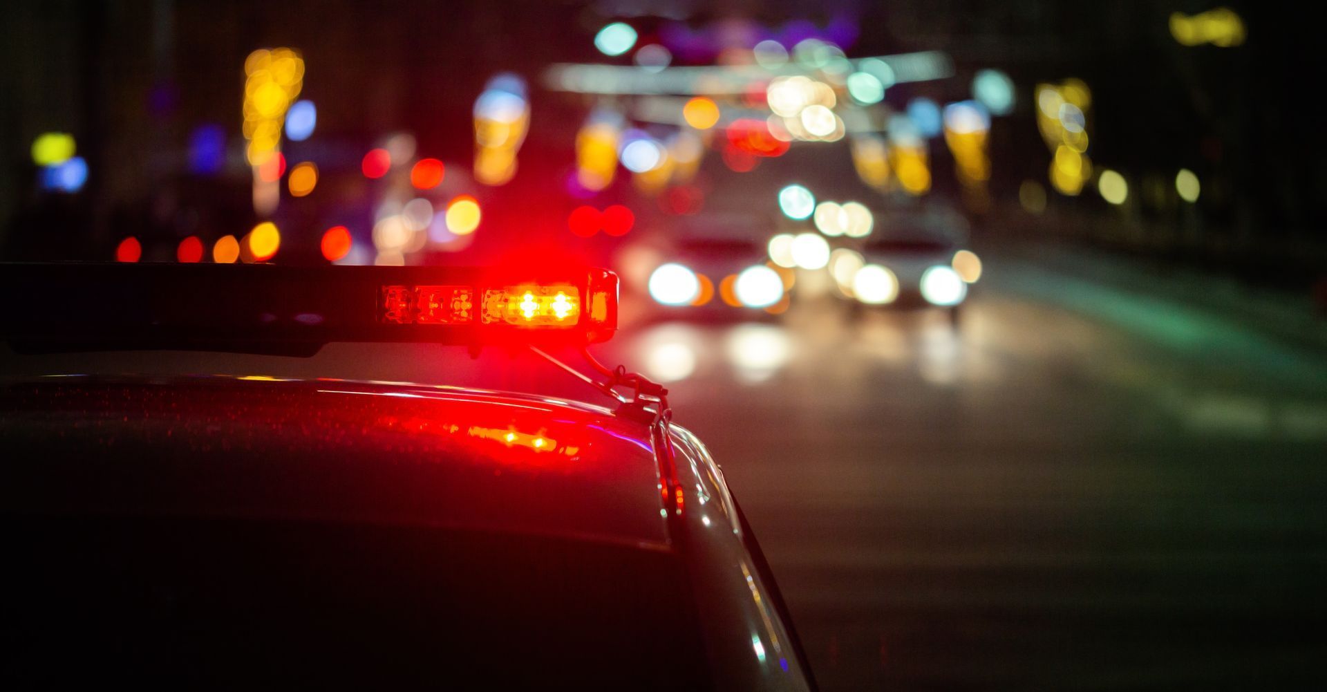A police car is driving down a city street at night.