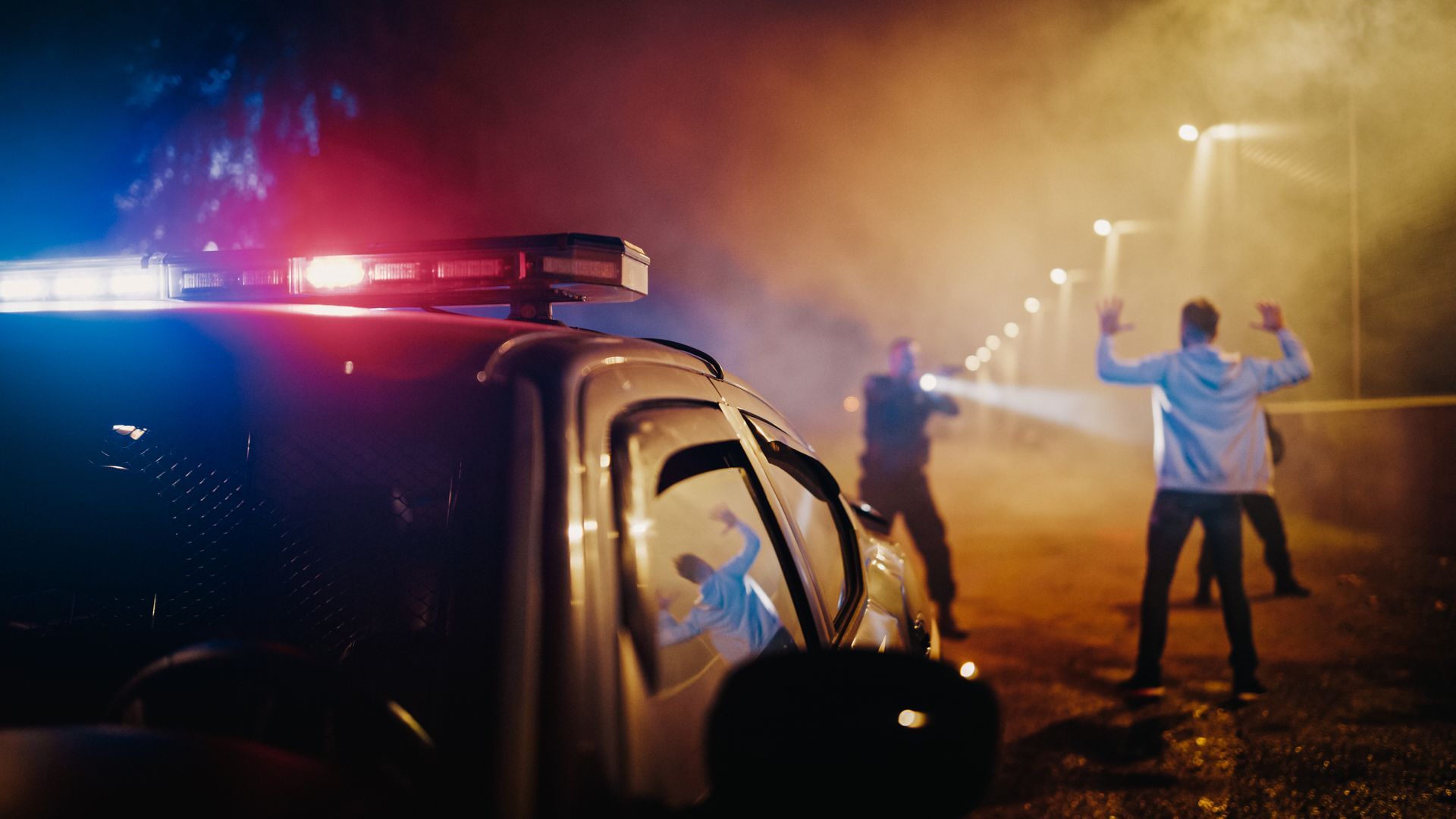 A police car is parked next to a group of people standing in front of it.