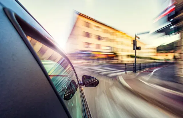 A blurry picture of a car driving down a city street.