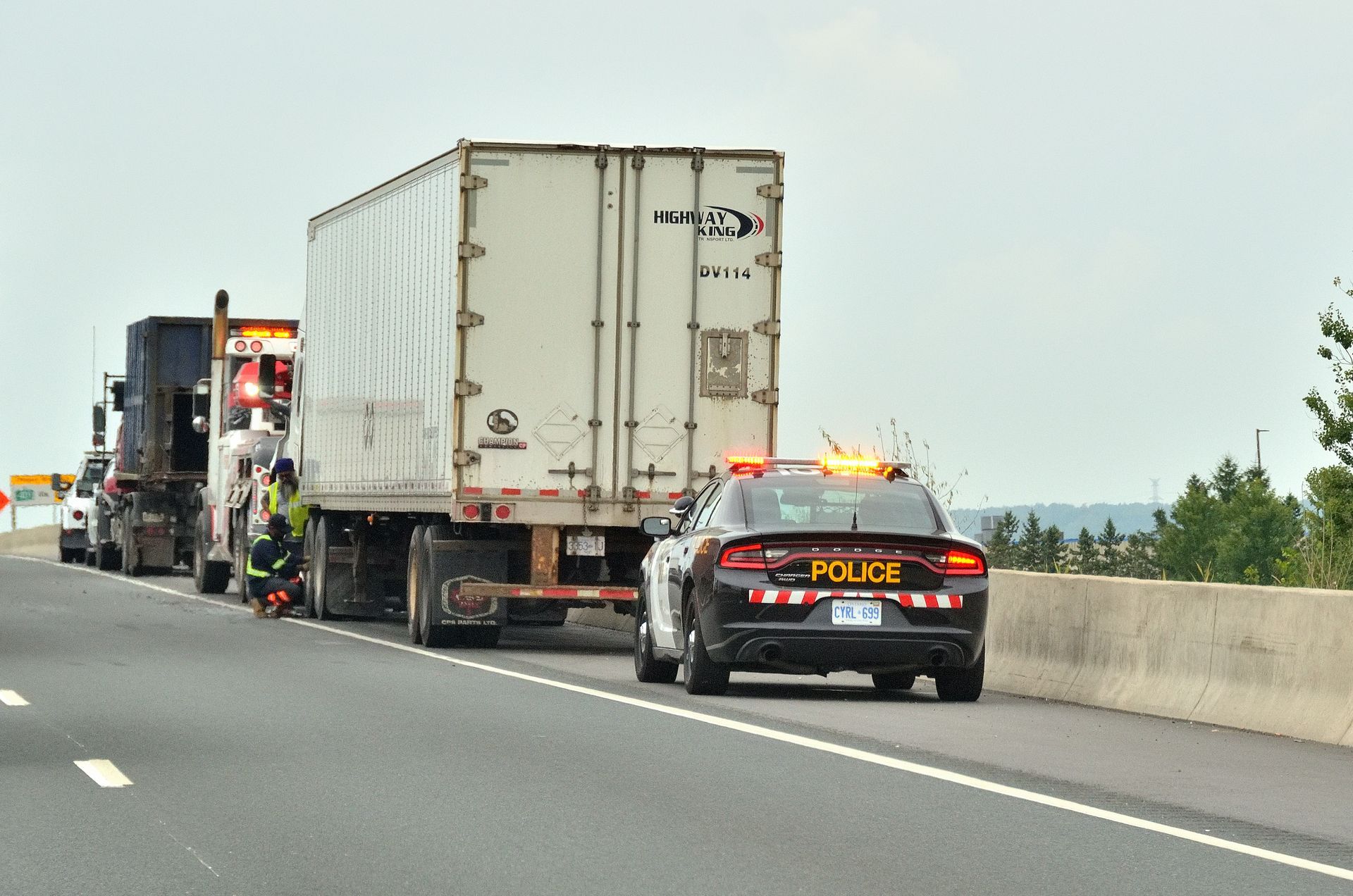 A police car is driving down a highway next to a semi truck