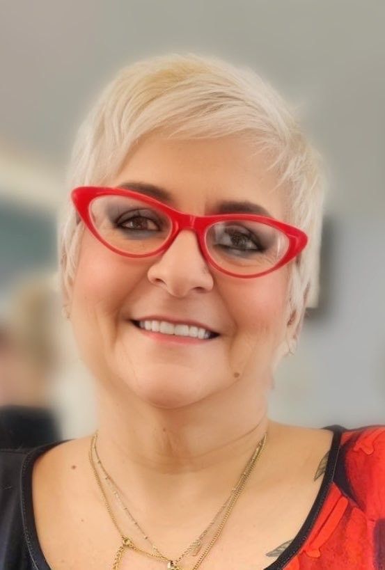 a woman wearing red glasses and a red shirt is smiling