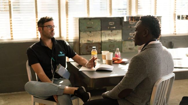 Two men are sitting at a table having a conversation.