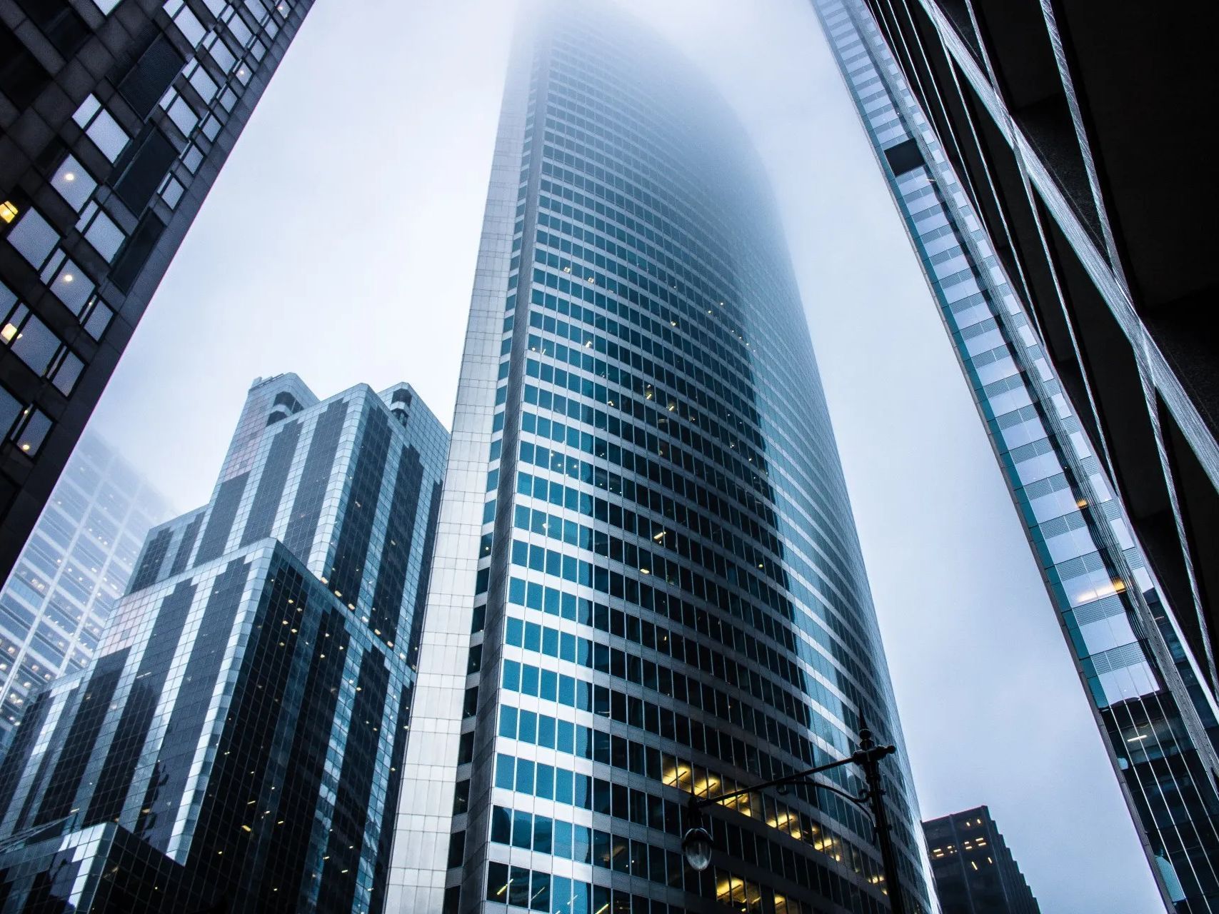 Looking up at a tall building in a city on a foggy day.