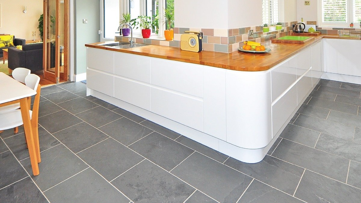 Kitchen with white cabinets, wooden countertop, and gray tiled floor.