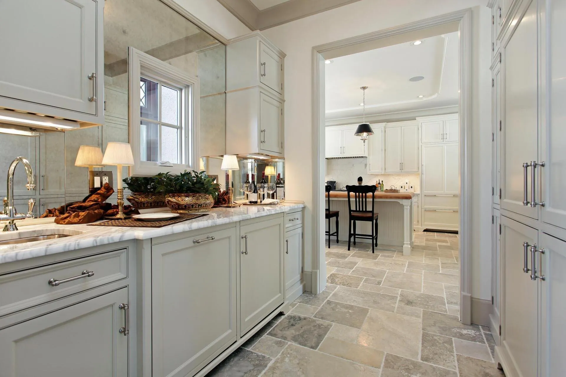 A kitchen with white cabinets , marble counter tops , and tile floors.