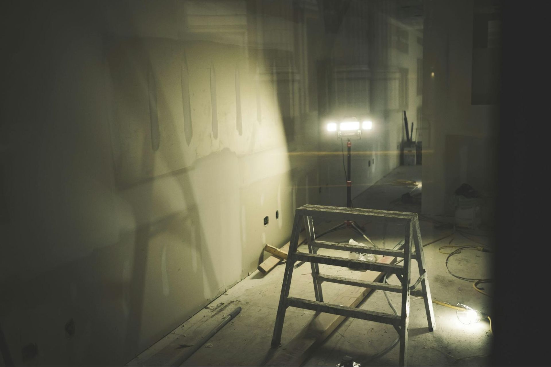 A ladder is sitting in a dark room next to a light.