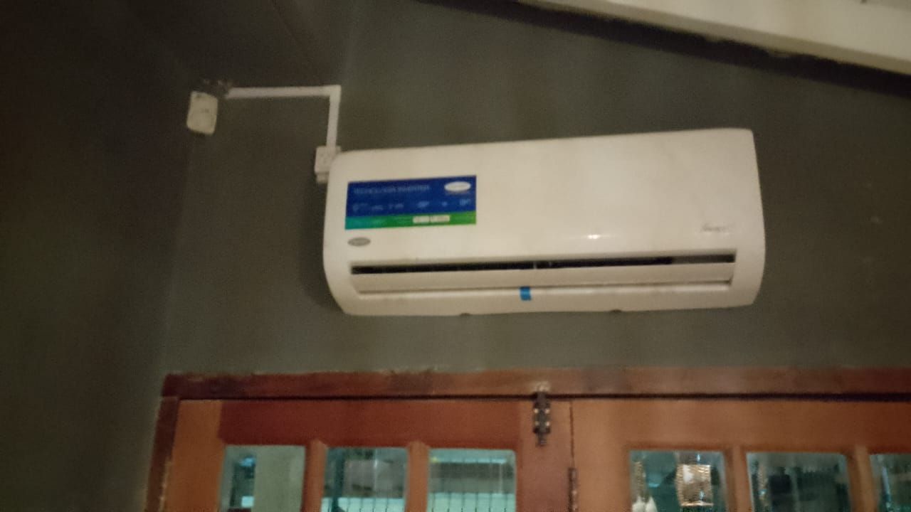 Unidad de aire acondicionado blanca montada en una pared gris sobre puertas de madera.