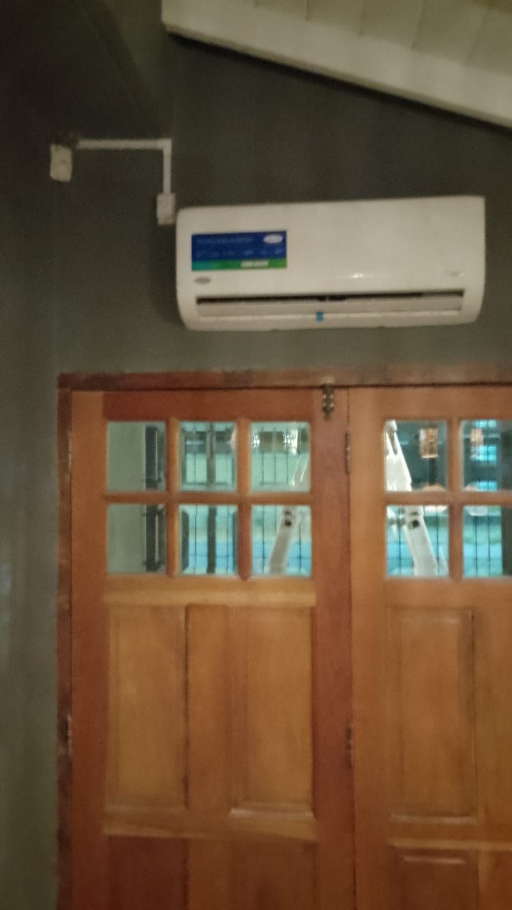 Aire acondicionado sobre puertas dobles de madera. Conducto eléctrico desde arriba.