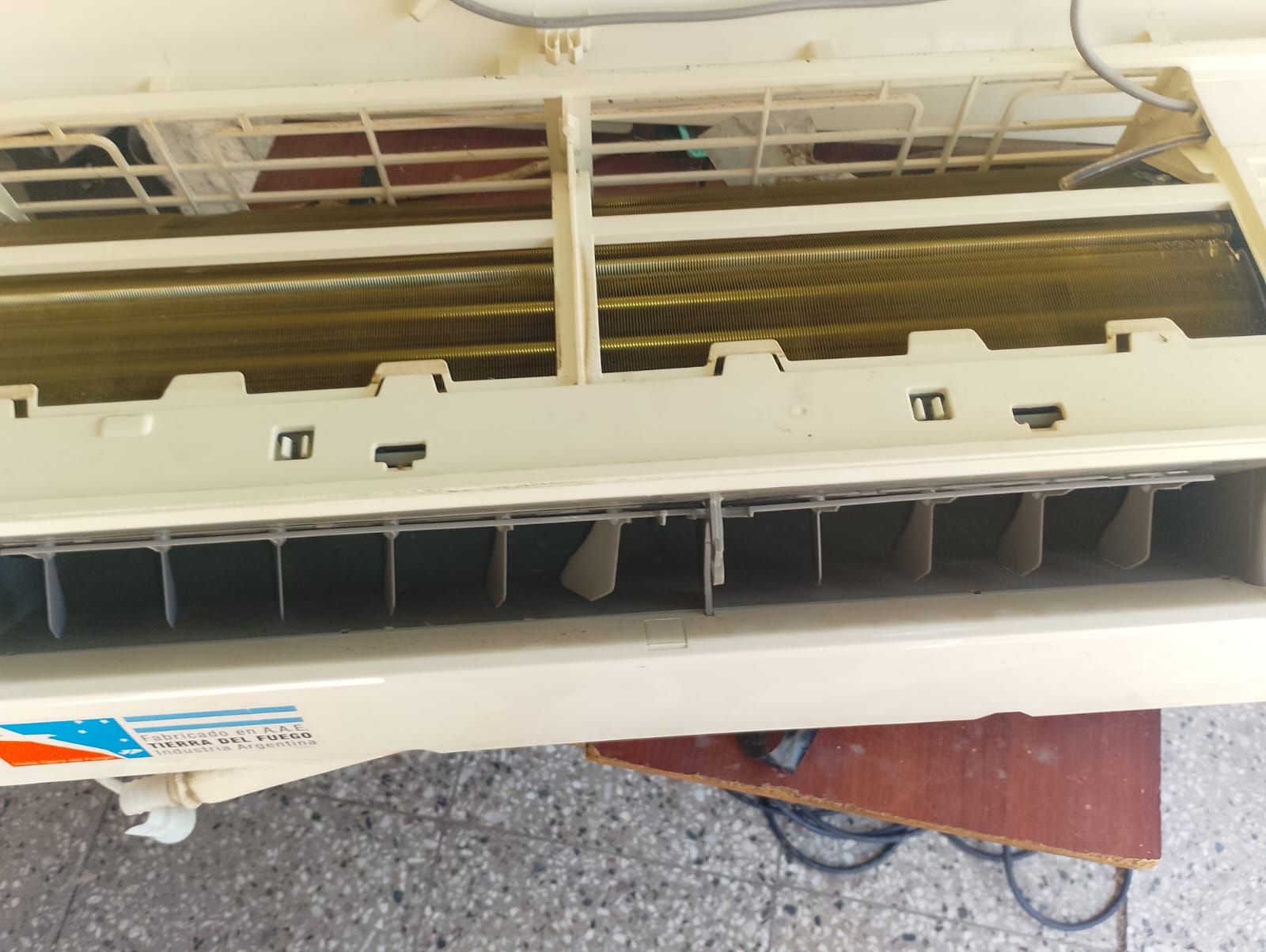 Interior del aire acondicionado, mostrando las rejillas de ventilación y los serpentines de refrigeración. Detalles de plástico beige, metal y alambre.