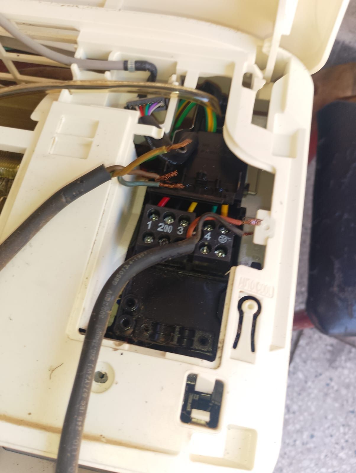 Cableado del aire acondicionado dañado, con plástico quemado y cables expuestos dentro de la unidad.