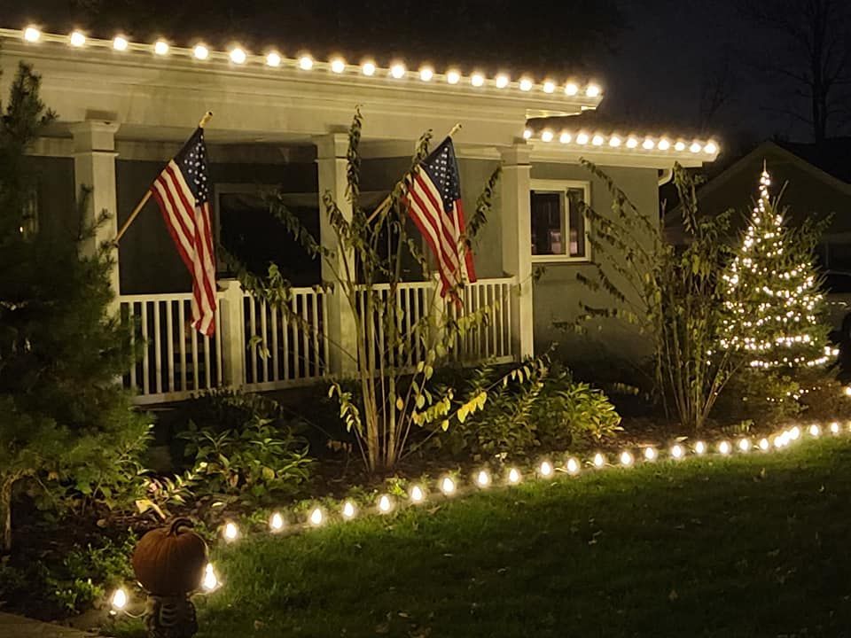 House decorated with string lights and American flags at night.