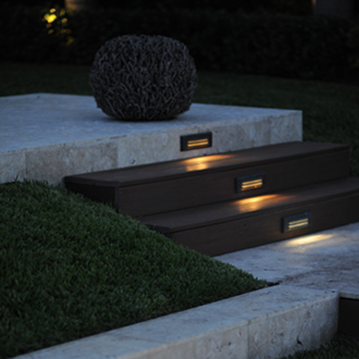 Outdoor steps with built-in lights, grass, and a decorative sphere. The steps are illuminated.