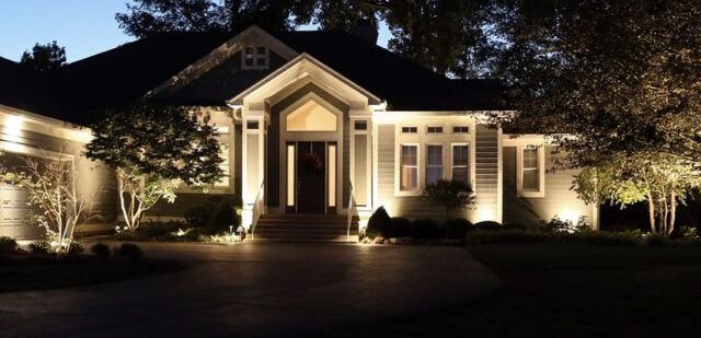 House illuminated at dusk with landscape lighting.
