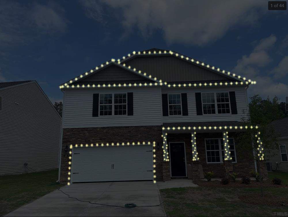 House decorated with white Christmas lights along the roofline, windows, and pillars against a night sky.