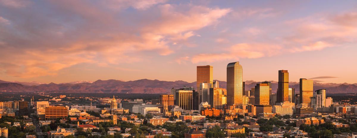 An aerial view of a city skyline at sunset with mountains in the background.