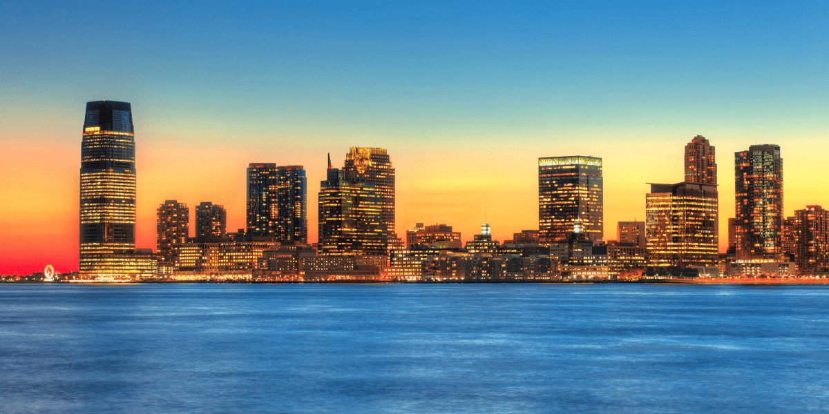 A city skyline is visible over a body of water at sunset.
