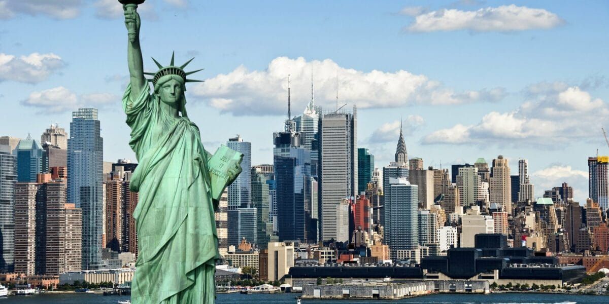 The statue of liberty is in front of a city skyline.