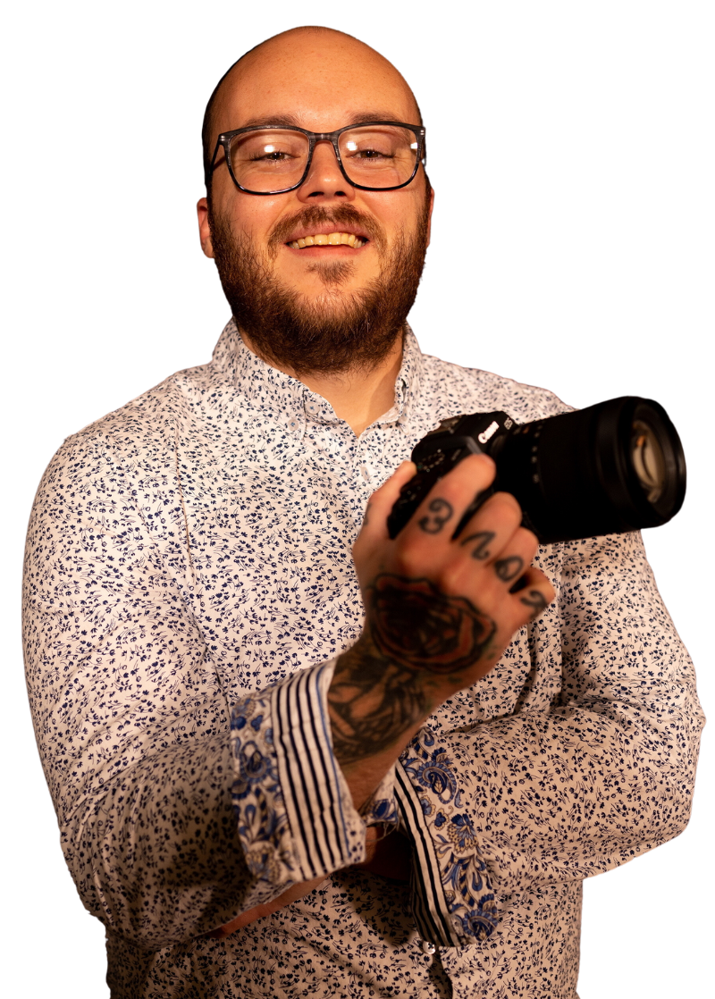 a man with a beard and glasses is holding a camera .