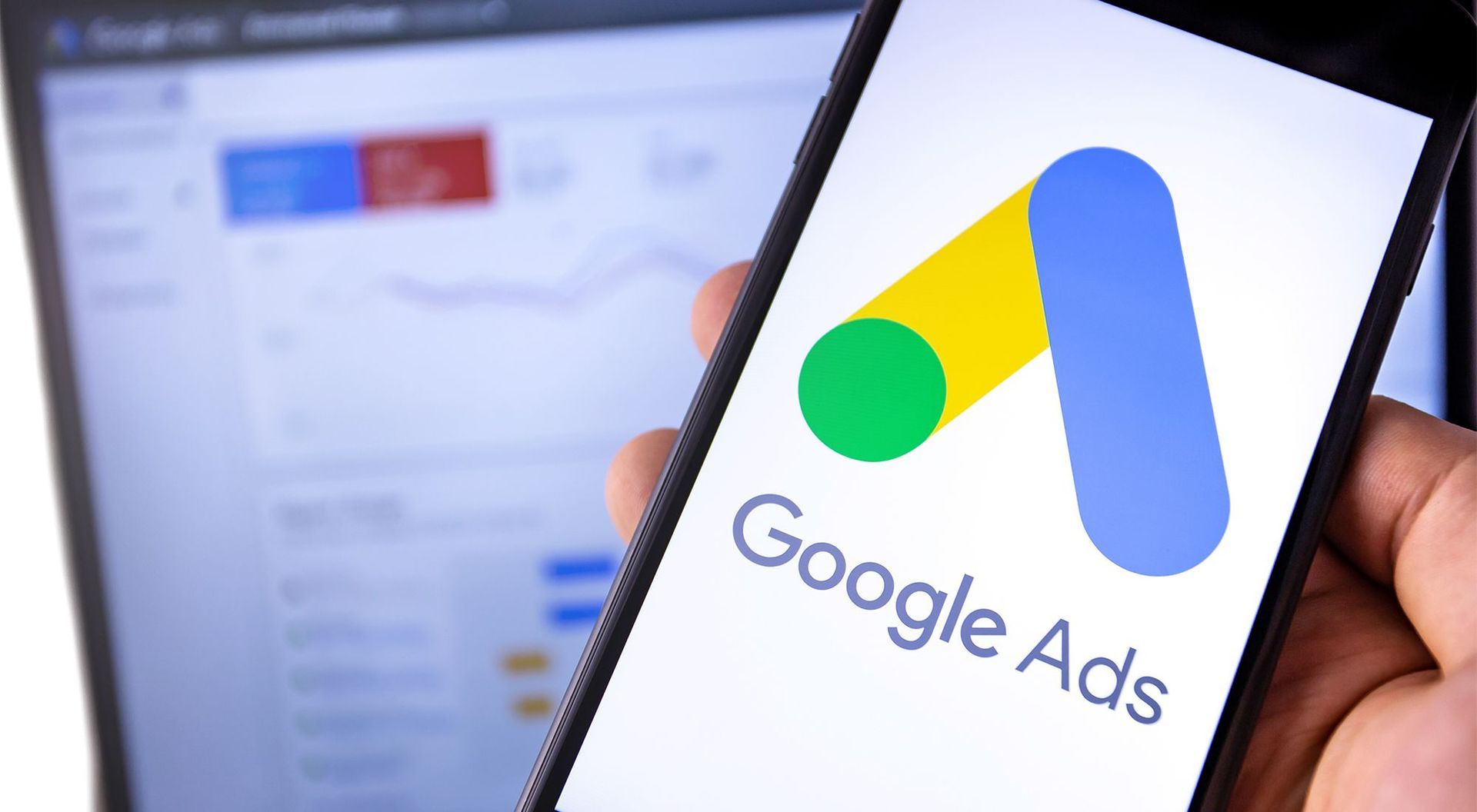 A person is holding a cell phone with the google ads logo on it.