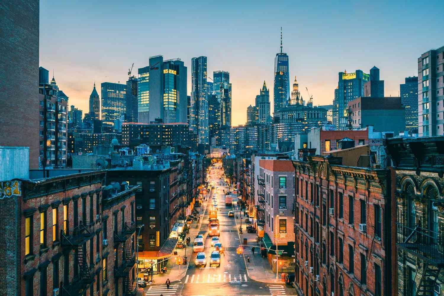 An aerial view of a city street at night with a skyline in the background.