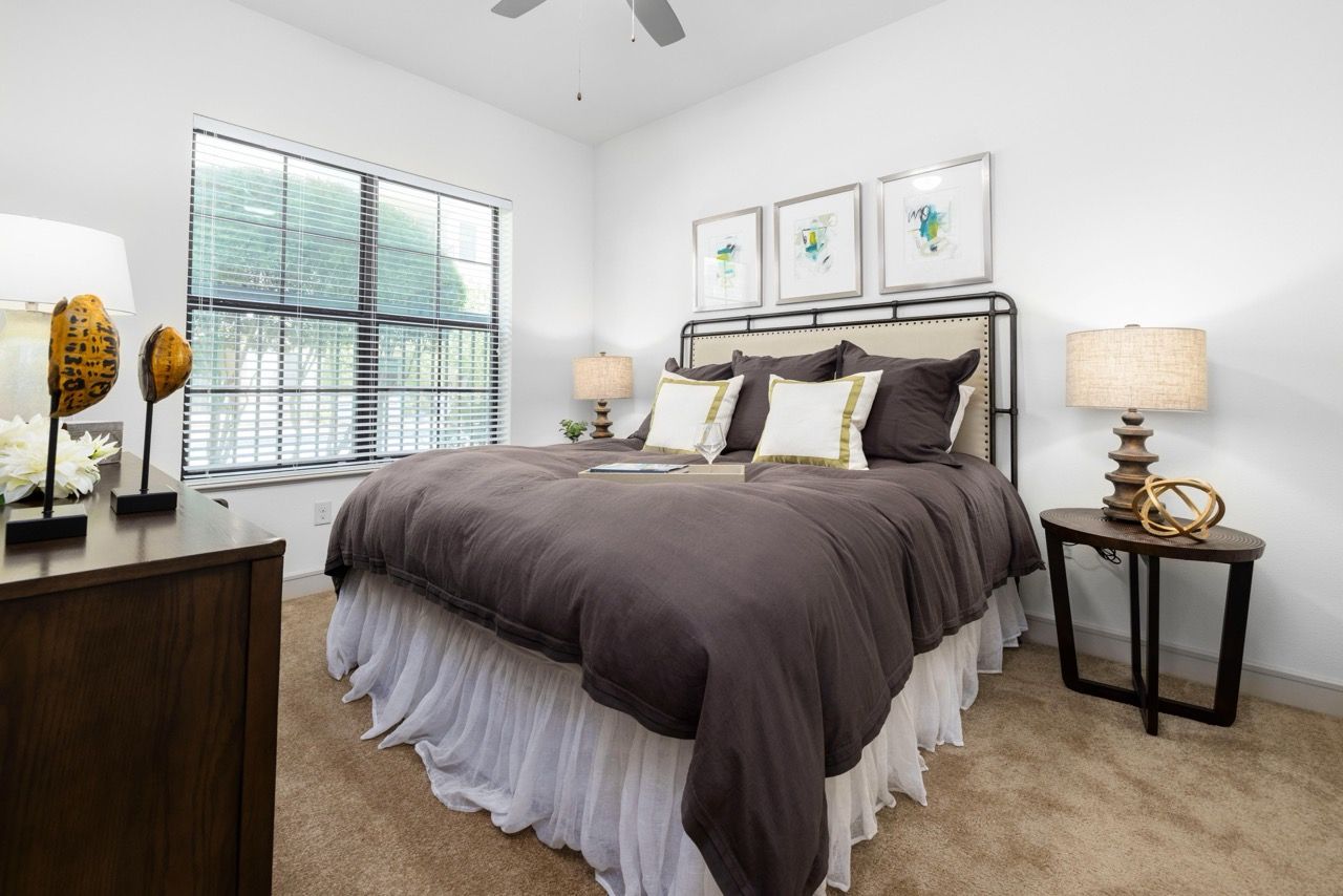 Bedroom featuring a large window, brown comforter, white bed skirt, and two nightstands.