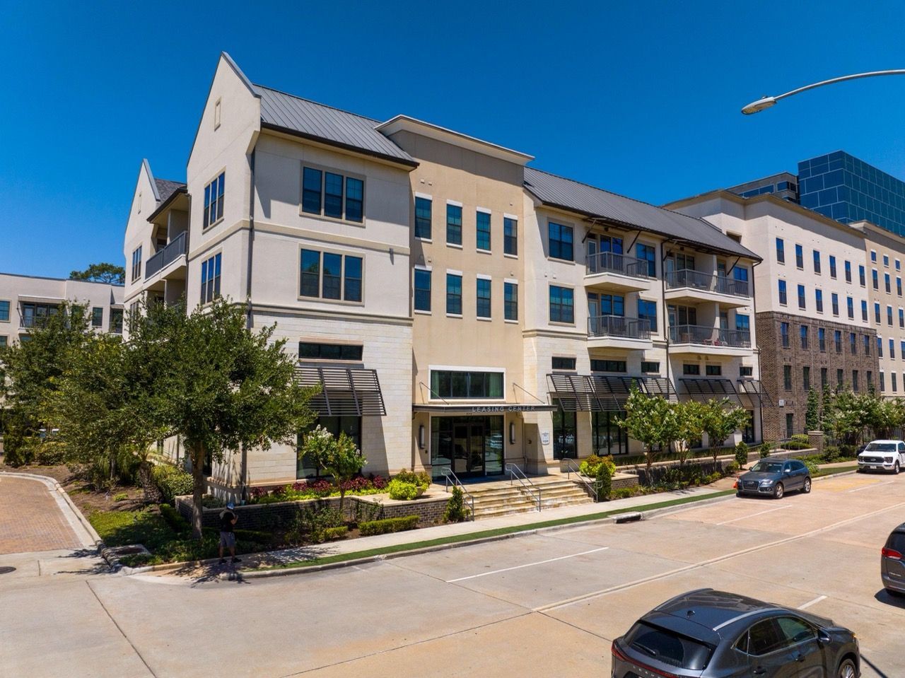 Exterior view of a modern apartment building with balconies and a bright blue sky.