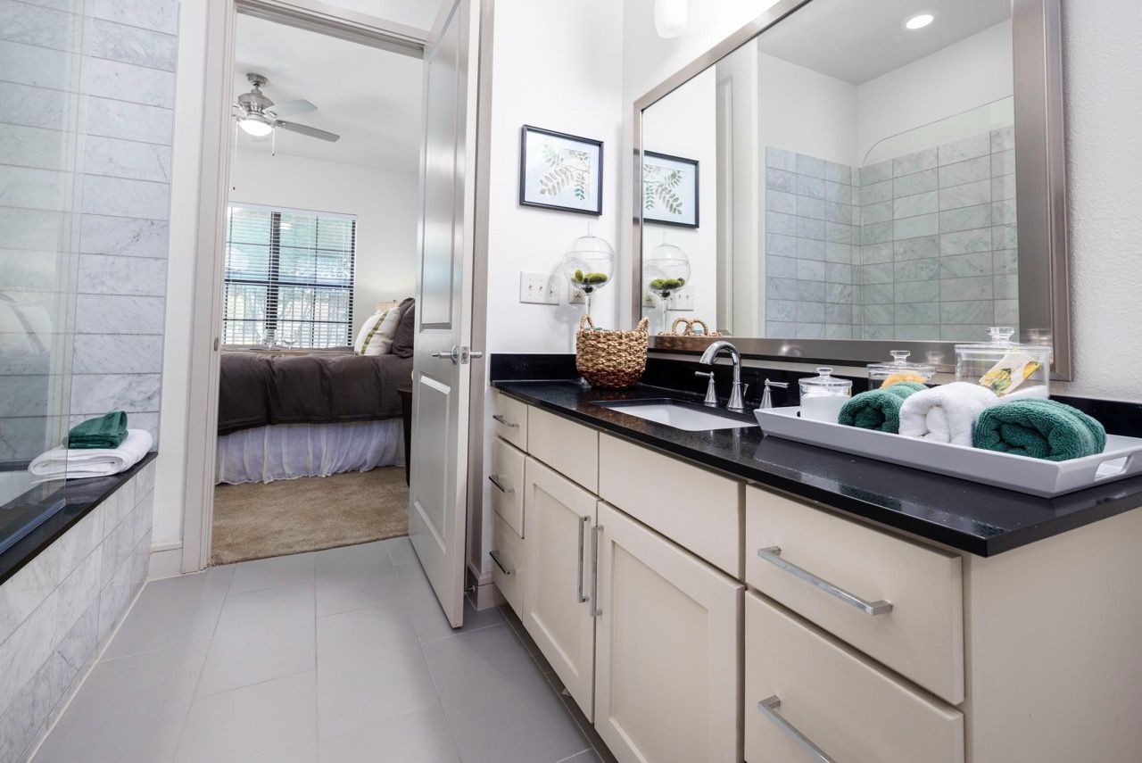 Bathroom vanity with sink, large mirror, and doorway to bedroom.