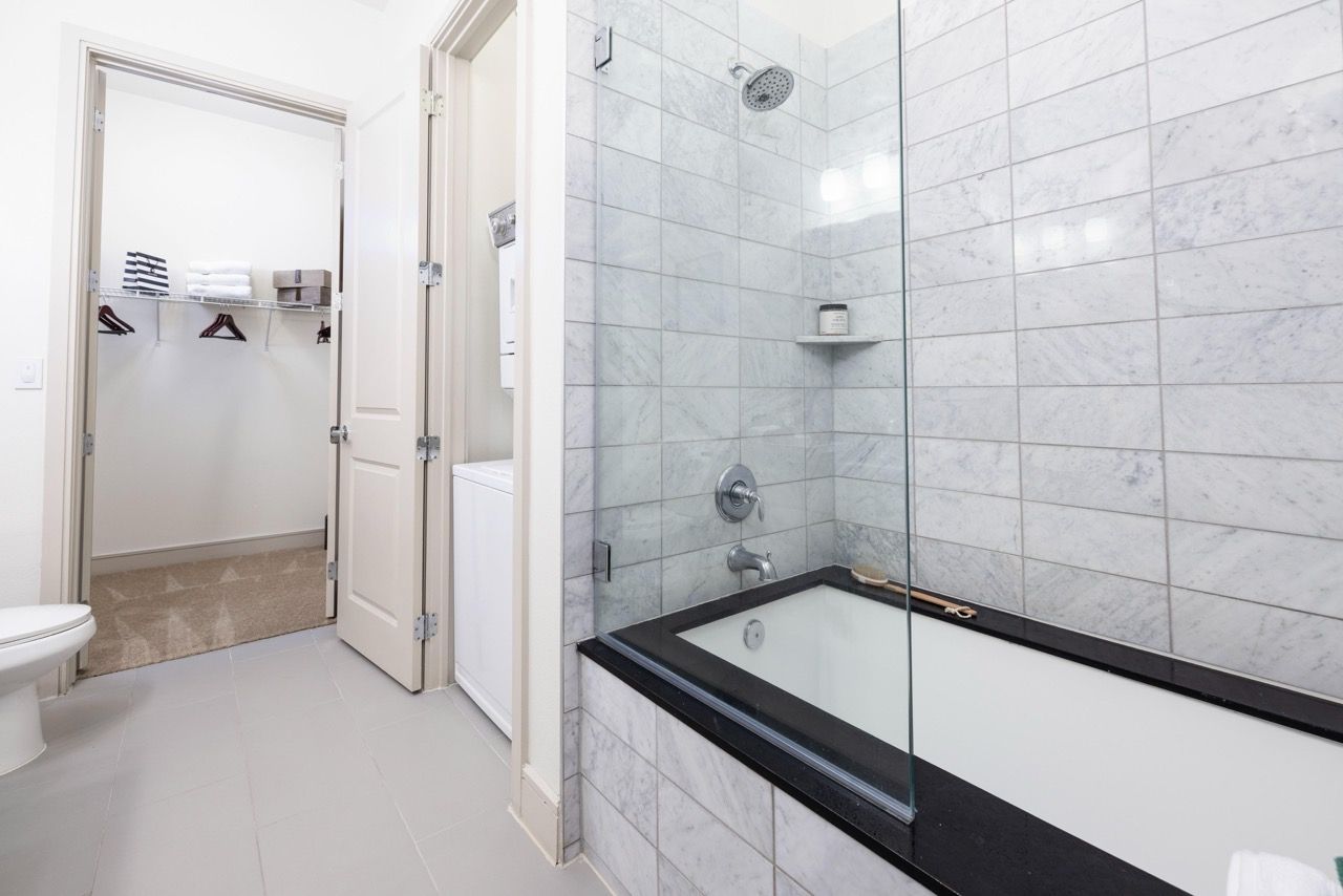 Bathroom with glass-enclosed tub/shower and adjacent closet area.