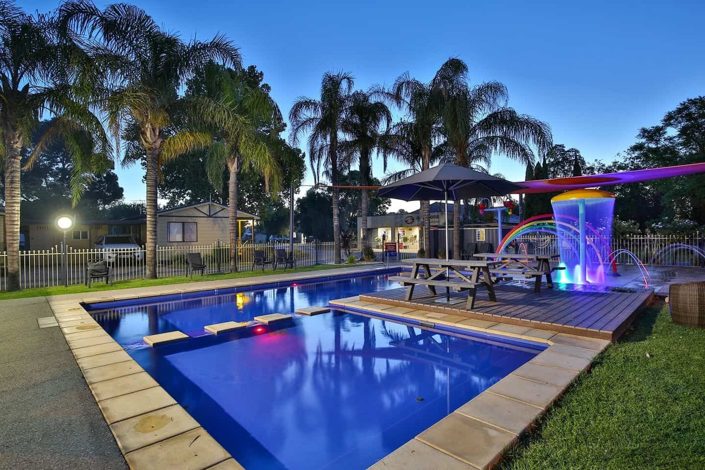 A Large Swimming Pool With Palm Trees in the Background — Pooltech NT In Alawa, NT