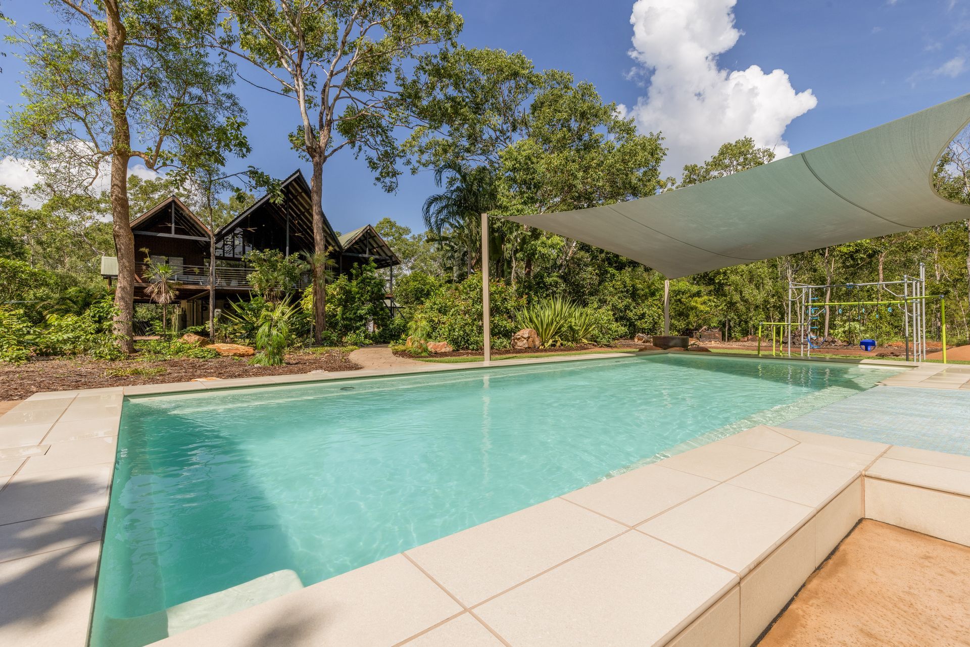 A Large Swimming Pool with A Canopy Over It and A House in The Background — Pooltech NT In Alawa, NT