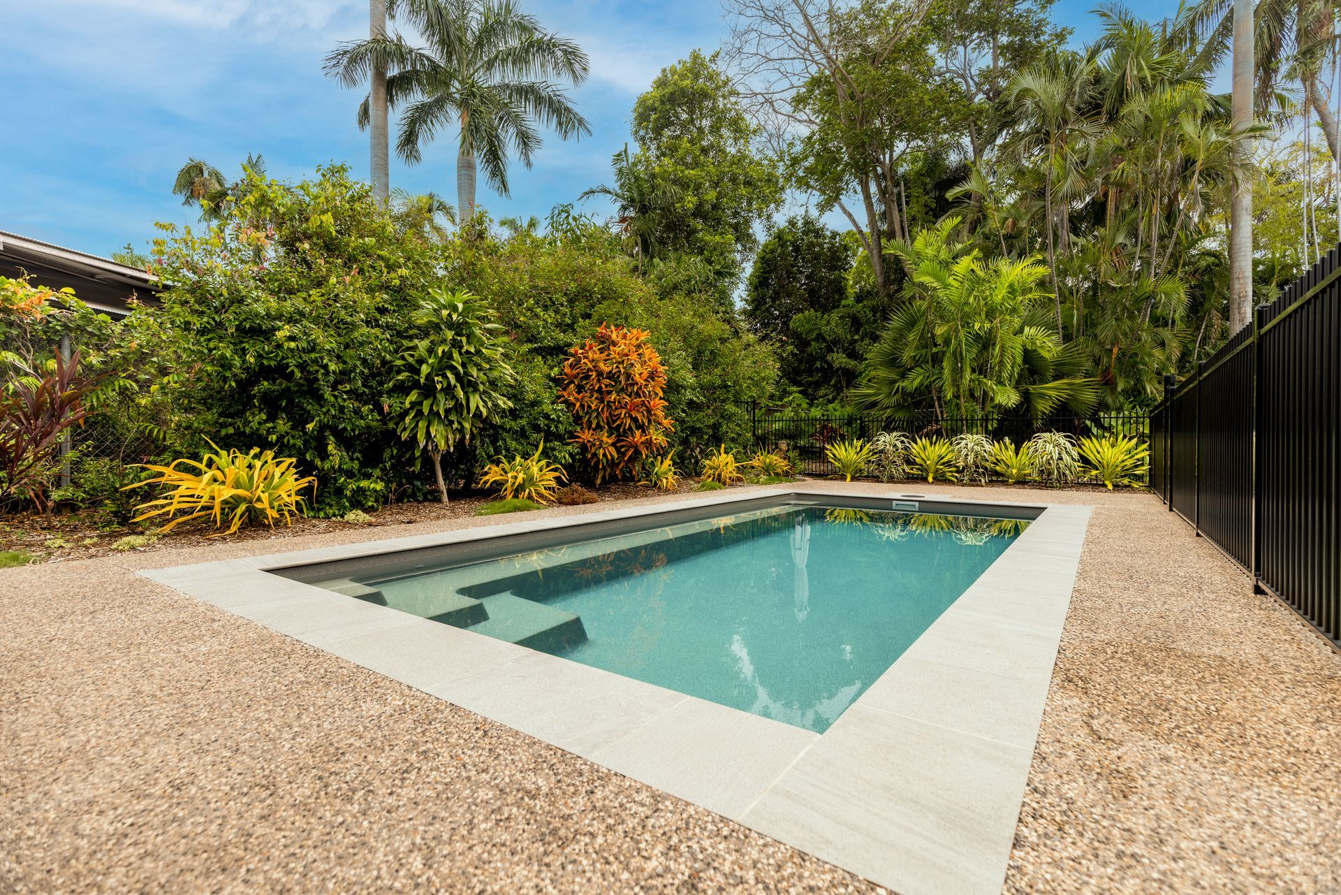 A Large Swimming Pool Surrounded by Trees and Bushes in A Backyard — Pooltech NT In Alawa, NT