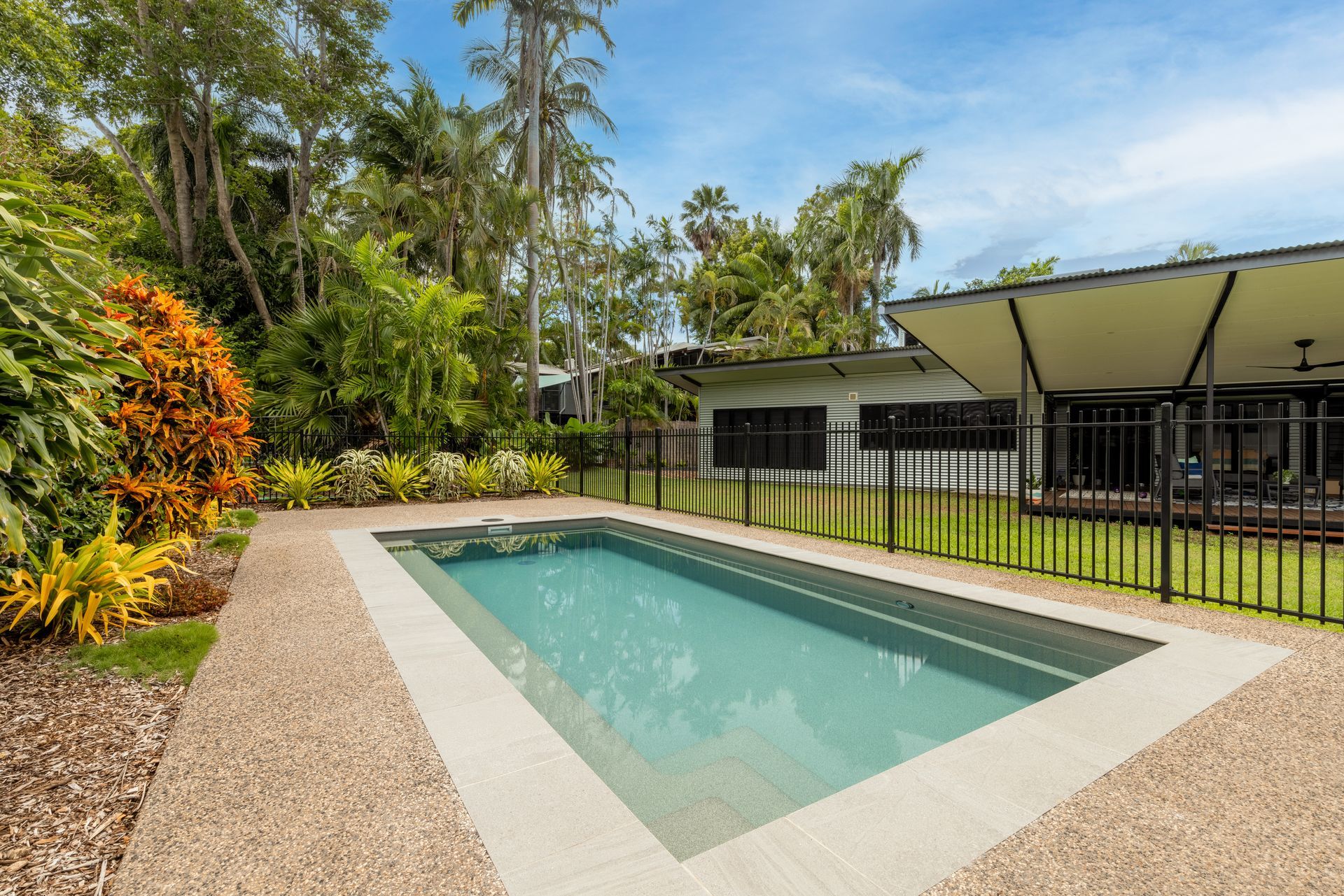 A Large Swimming Pool Is Surrounded by A Fence in Front of A House — Pooltech NT In Alawa, NT