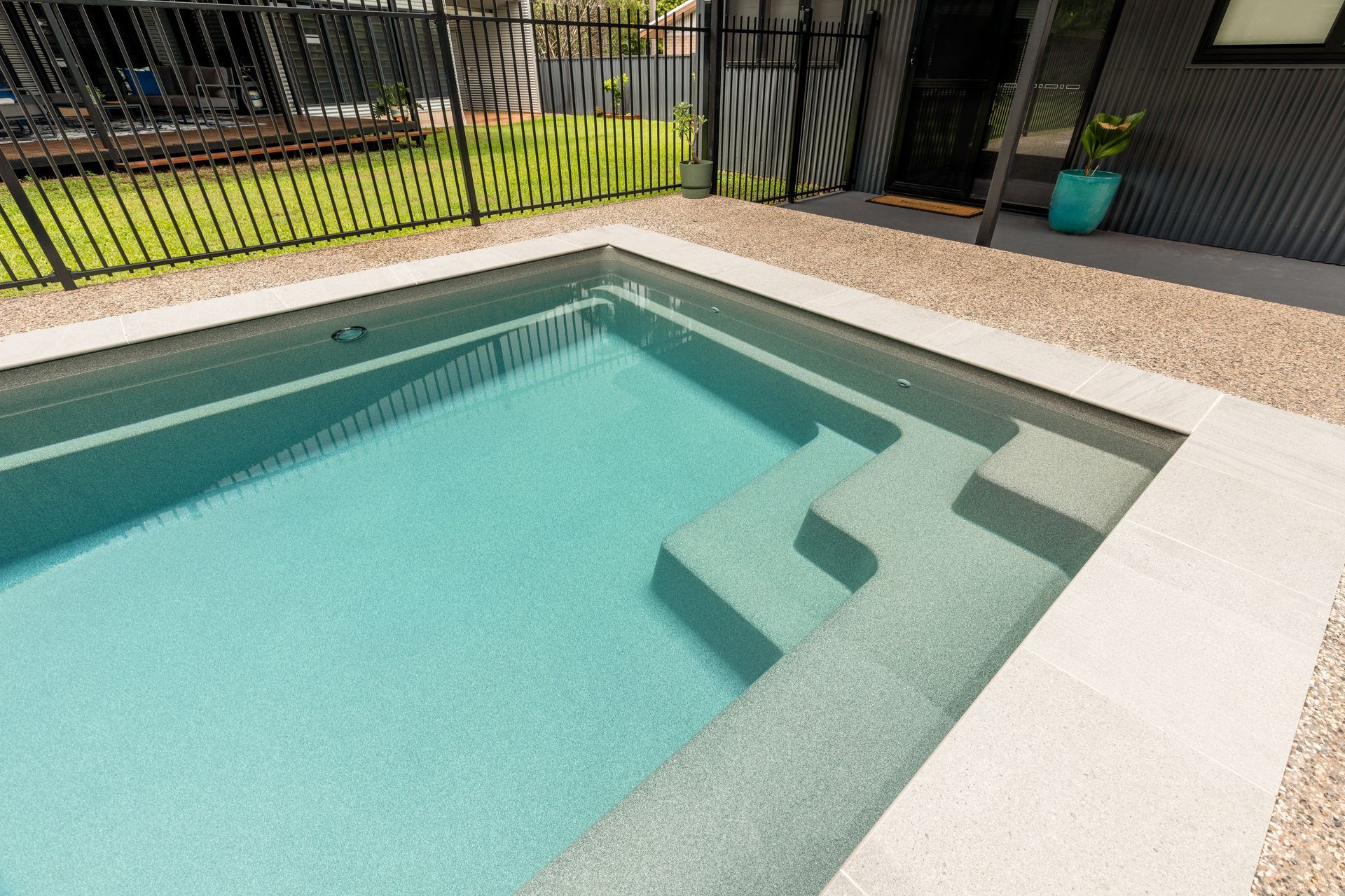 A Swimming Pool with Stairs and A Fence in The Backyard of A House — Pooltech NT In Alawa, NT