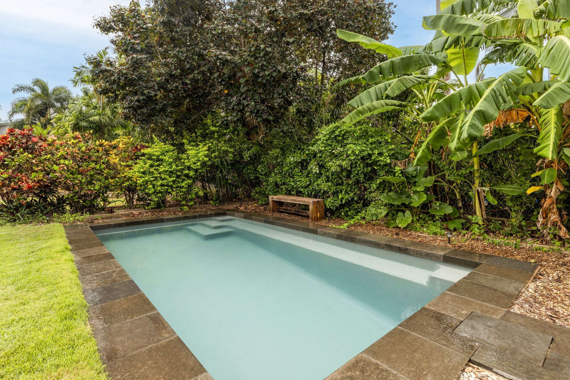 A Large Swimming Pool Surrounded by Trees and Bushes in A Backyard — Pooltech NT In Alawa, NT