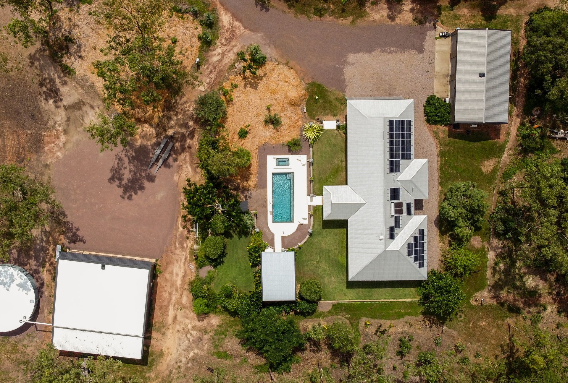 An Aerial View of A House with A Pool in The Middle of A Lush Green Field — Pooltech NT In Alawa, NT
