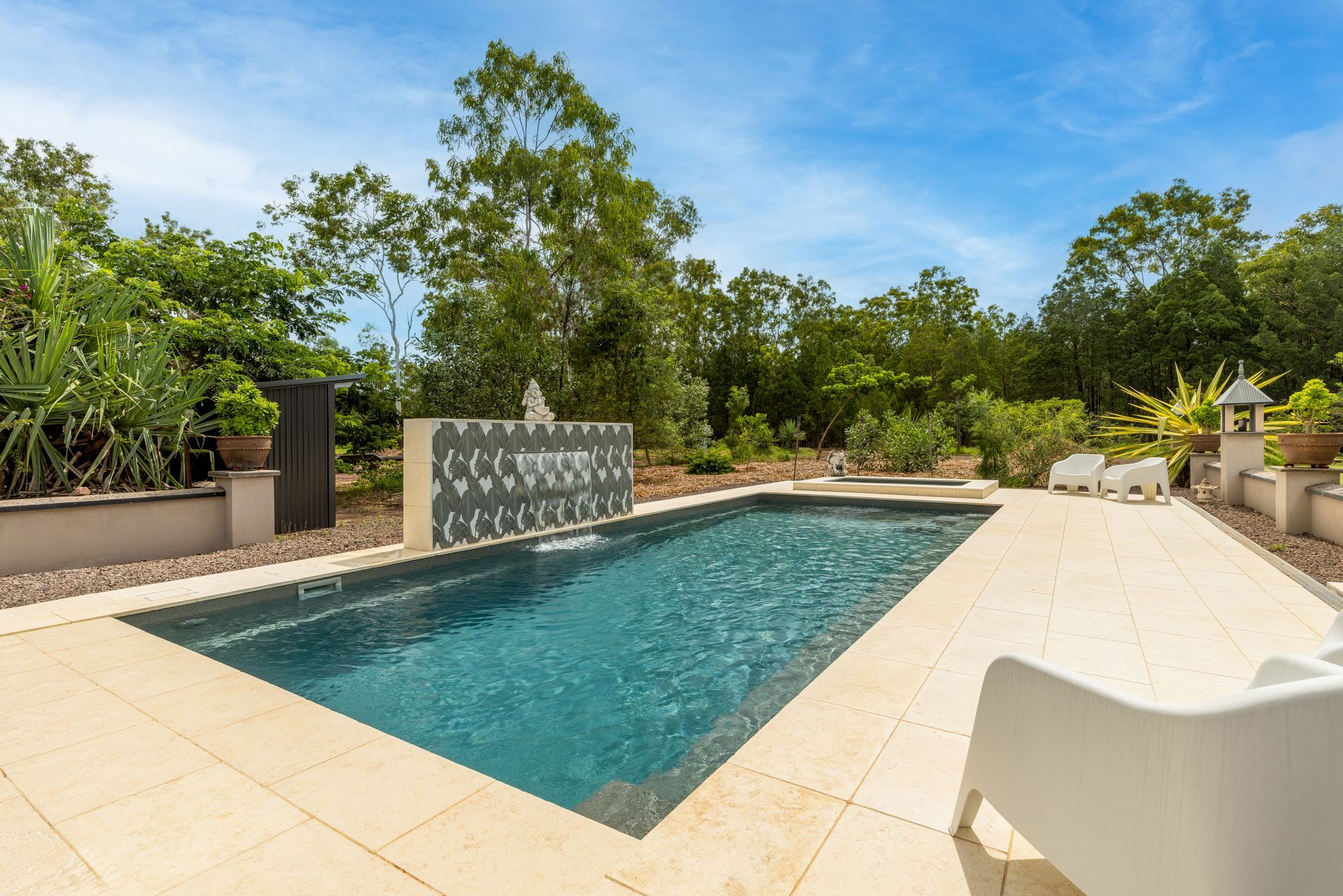 A Large Swimming Pool Is Surrounded by Trees and A White Chair — Pooltech NT In Alawa, NT