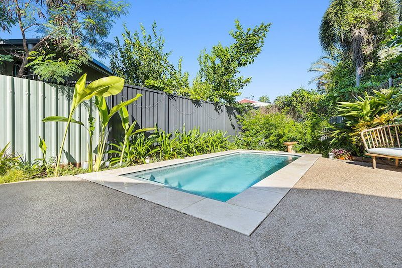 A Large Swimming Pool is Surrounded by a Fence and Trees — Pooltech NT In Alawa, NT