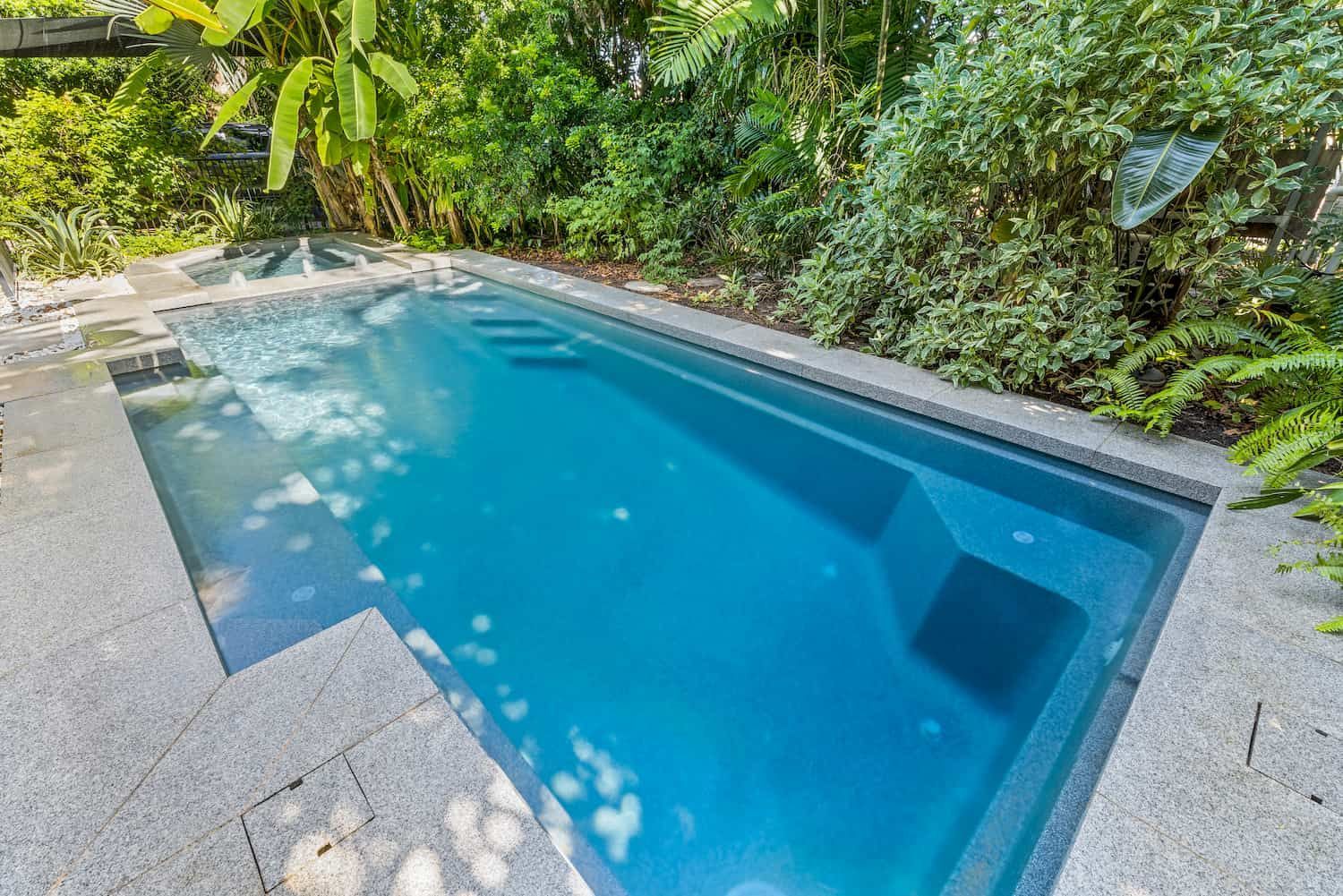 A Large Swimming Pool With Steps Surrounded by Trees and Bushes in a Backyard — Pooltech NT In Alawa, NT