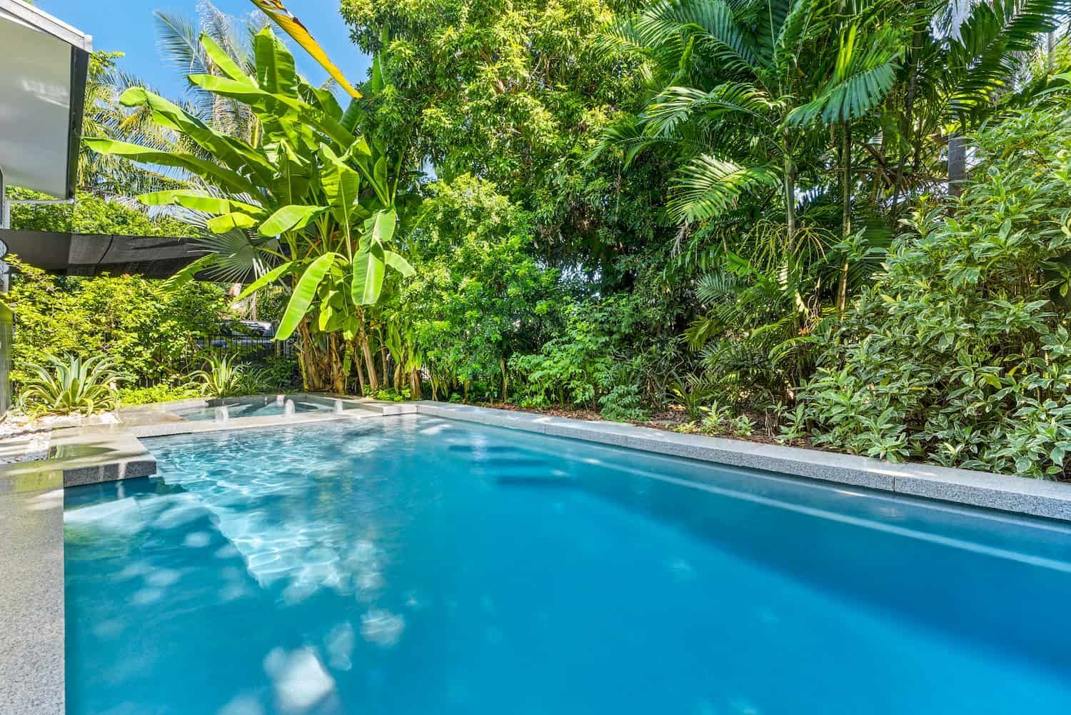 A Large Swimming Pool Surrounded by Trees and Bushes in a Backyard — Pooltech NT In Alawa, NT