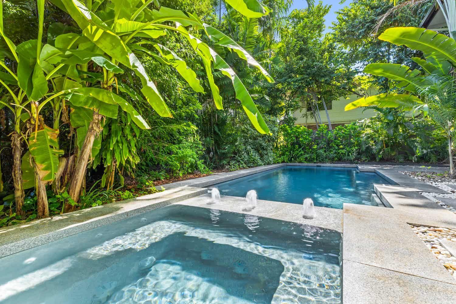 A Large Swimming Pool With a Hot Tub in the Backyard Surrounded by Trees — Pooltech NT In Alawa, NT